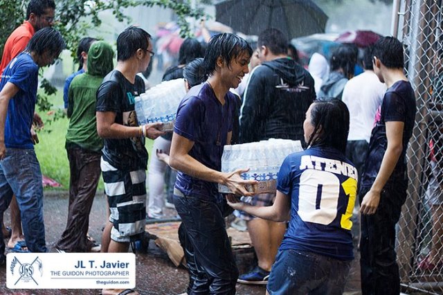 Volunteers pass cases of bottled water in an assembly line despite the torrential rains. Photo by John Lorenzo Javier (Guidon)