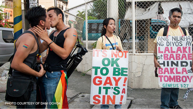 Jake Jereza (right) and his boyfriend Bardo Wu (left) kiss during a Pride March photo in front of some protesters. 